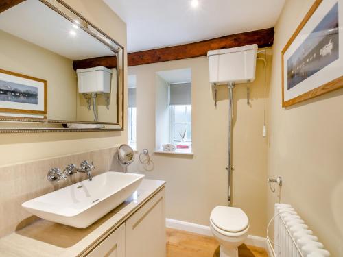 a bathroom with a sink and a toilet and a mirror at Forge Cottage in Carlton