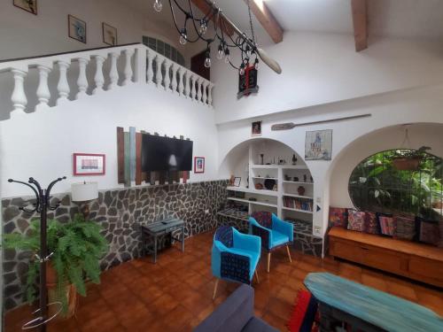 a living room with two blue chairs and a tv at El Castillo en el Lago Atitlán in San Marcos La Laguna