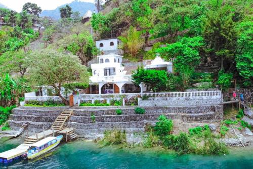 una casa en el río con un barco en el agua en El Castillo en el Lago Atitlán en San Marcos La Laguna