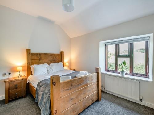 um quarto com uma grande cama de madeira e uma janela em Veras Cottage em Edale