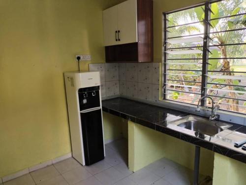 una pequeña cocina con fregadero y nevera. en HOMESTAY ADRA LEBAN CHONDONG ROMPIN, en Kuala Rompin