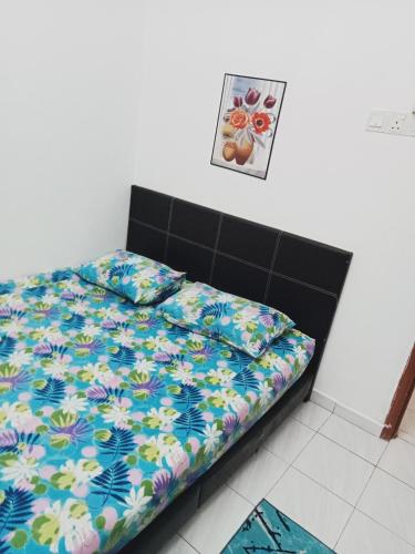 a bed with a colorful comforter in a room at HOMESTAY CAHAYA PUTERI in Tangga Batu