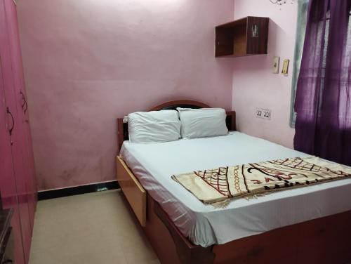 a small bedroom with a bed with white sheets at Joe Niwas villa 3bhk in Puducherry