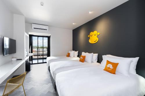 a room with three beds and a wall with a yellow face on it at Newly Opened - Blu Monkey Hub and Hotel Krabi Town in Krabi