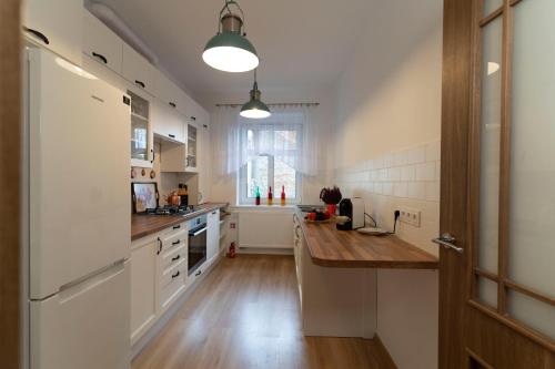 a kitchen with white cabinets and a wooden counter top at Apartament przy Czarnej Bramie in Kłodzko