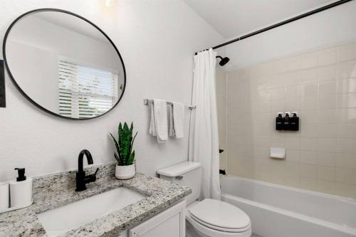 Un baño blanco con lavabo y espejo. en Golden Chest - Modern - UTSA Central - Fast WiFi, en San Antonio