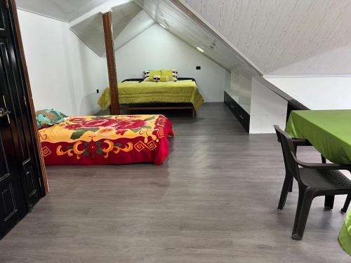 a attic bedroom with two beds and a table at Casa de Campo Guayllabamba in Quito