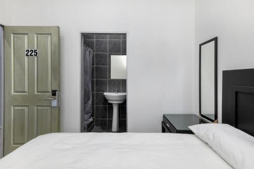 um quarto com uma cama e uma casa de banho com um lavatório em Inn & Out Express Sea Point na Cidade do Cabo