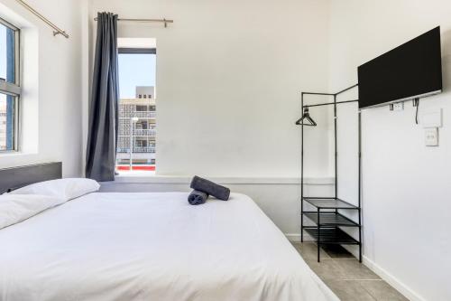 a bedroom with a white bed and a flat screen tv at Inn & Out Express Sea Point in Cape Town