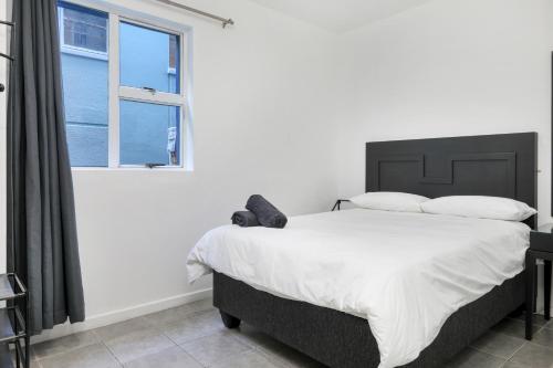 a bedroom with a bed with white sheets and a window at Inn & Out Express Sea Point in Cape Town