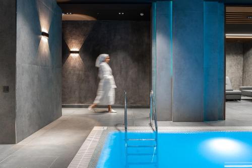 a woman walking past a swimming pool in a building at Europe Hotel Tashkent in Tashkent