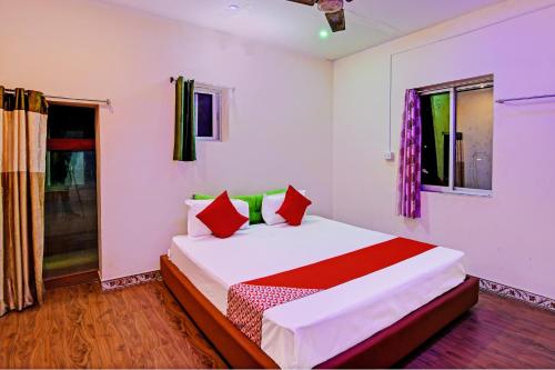 a bedroom with a bed with red and green pillows at OYO Flagship Hotel Daffodil Lodging and Boarding in Jānla