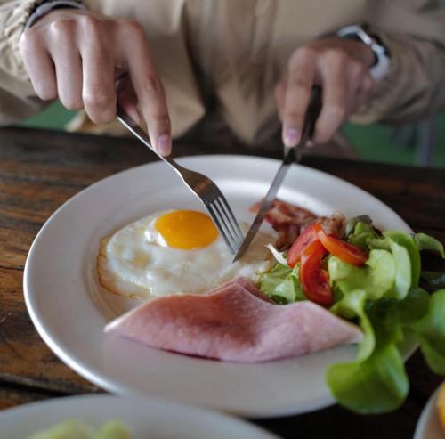 une personne qui mange un plat avec des œufs et de la salade dans l'établissement Black Bear House Resort & Onsen, à Chiang Dao