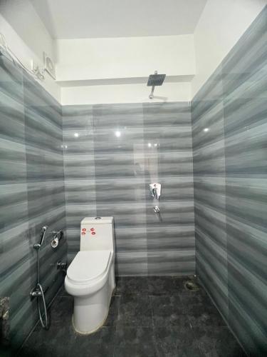 a bathroom with a toilet with gray stripes on the wall at Hotel Manikut in Rishīkesh