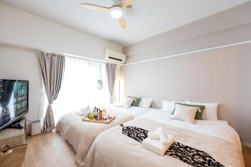 a bedroom with two beds and a tv at Beige in Tokyo