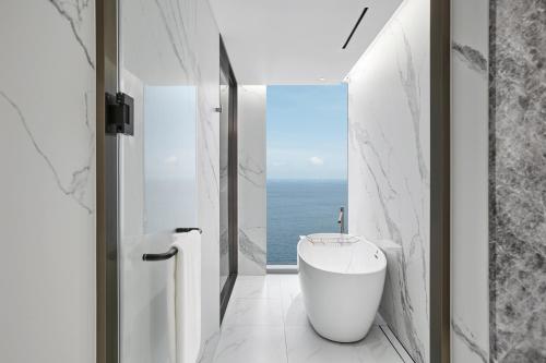 a bathroom with a tub and a view of the ocean at Wyndham Grand Busan in Busan