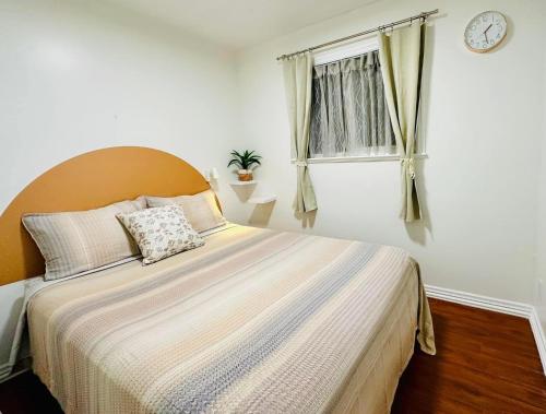 a bedroom with a large bed with a clock on the wall at 2BR 1BA Guest Suite - Free Parking - Central Location w/ Mountain-View in Vancouver