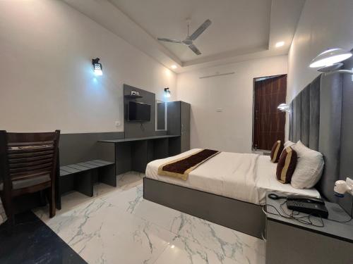 een slaapkamer met een bed, een bureau en een televisie bij Hotel Embassy in Dehradun