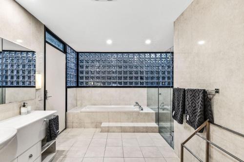 ein Bad mit einer Badewanne, einer Dusche und einem Waschbecken in der Unterkunft Orton Oceanview Luxury Retreat in Ocean Grove