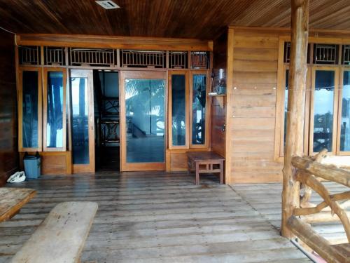 a porch of a wooden house with glass doors at Kutnalek Surf Camp Siberut Mentawai front Beach,Green Village,front Wave for surfing in Masokut