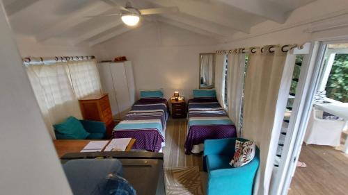 a room with four beds and chairs in it at Are Tamareni River Studio in Avarua