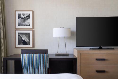 a hotel room with a bed and a tv and a desk at Moana Surfrider, A Westin Resort & Spa, Waikiki Beach in Honolulu