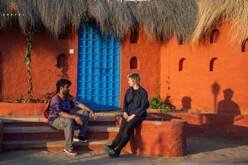 two men sitting on a bench in front of a building at Zostel Sam Desert (Jaisalmer) in Sām