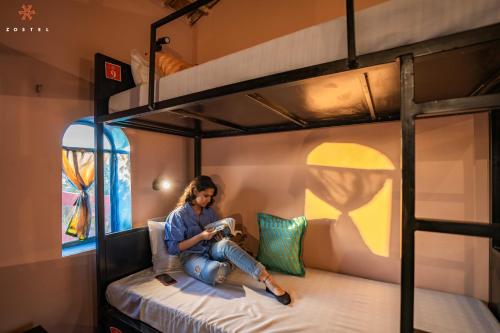 a woman is sitting on a bunk bed at Zostel Sam Desert (Jaisalmer) in Sām