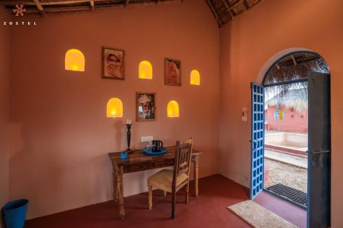 a room with a table and a chair and a window at Zostel Sam Desert (Jaisalmer) in Sām