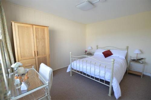 een slaapkamer met een wit bed en een houten kast bij Benvoy House apartment 