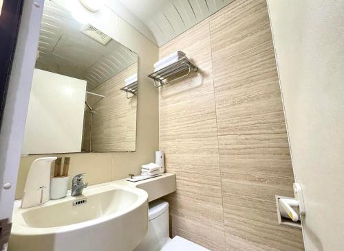 een badkamer met een wastafel, een toilet en een spiegel bij ADB TOWER in Manilla
