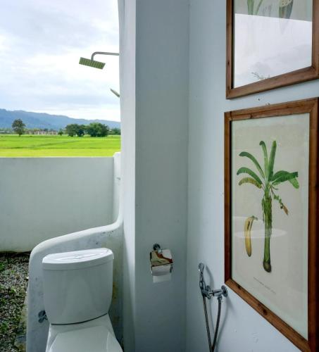 a bathroom with a toilet and a picture of a palm tree at The White House Homestay in Pantai Cenang