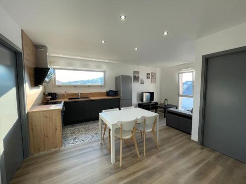 cocina y comedor con mesa blanca y sillas en Appartement climatisé en Charmes