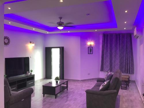 a living room with purple lights on the ceilings at Fine Boy Villa, Luxe Two-Bedroom Apartments in Tema Community 25 in Tema