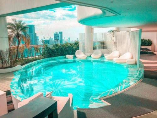 una gran piscina con sillas blancas en un edificio en Aveline Suites Modern Amenity View ACQUA Private Residences near Rockwell Makati, en Manila