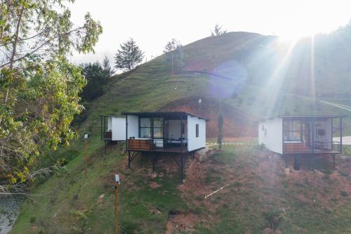 two tiny houses on a hill with the sun shining at Laze Lake Guatape in El Peñol