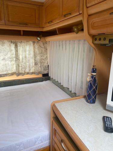 Dormitorio pequeño en una cabaña con cama en Wohnwagen auf dem Wulfenerhals, en Fehmarn