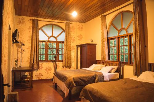 a bedroom with two beds and two windows at MF Holiday Bungalow in Bandarawela
