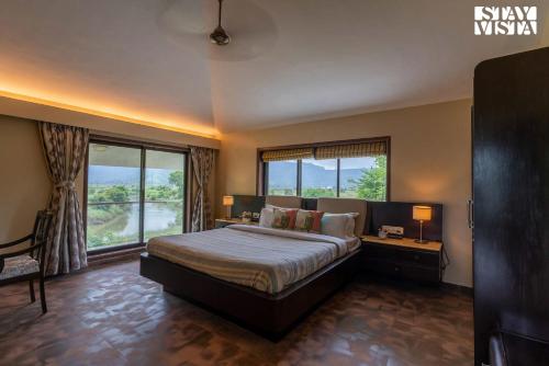a bedroom with a bed and a large window at River Song by VEO - Part of StayVista in Lonavala