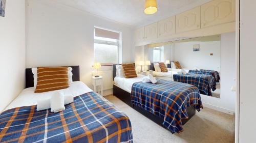 a hotel room with three beds and a mirror at Charming 5-Bed House in Grays in Grays Thurrock