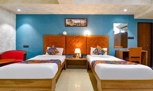 a hotel room with two beds and a desk at FabHotel Siddharth Corporate in Gandhinagar