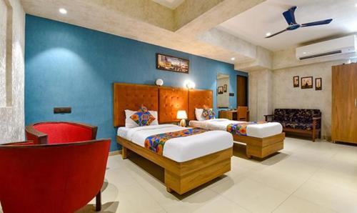 FabHotel Siddharth Corporate في غانديناغار: غرفة نوم بسريرين وكرسي فيها