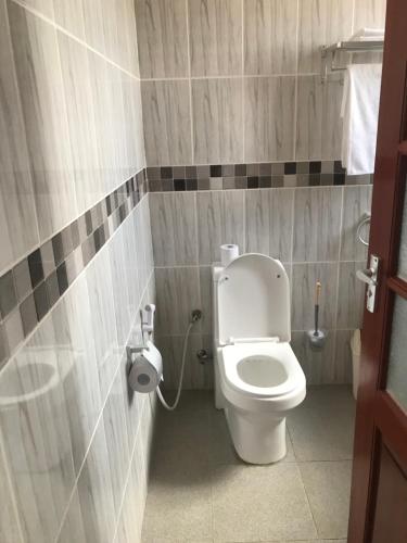 La salle de bains est pourvue de toilettes et d'un distributeur de papier toilette. dans l'établissement Lerai X Desty, à Arusha