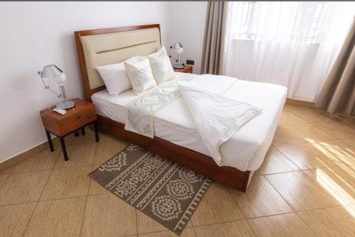 een slaapkamer met een groot bed en een nachtkastje met een lamp bij Lerai X Desty in Arusha