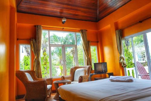 1 dormitorio con paredes de color naranja, 1 cama y ventanas en Keereeta Resort en Ko Chang