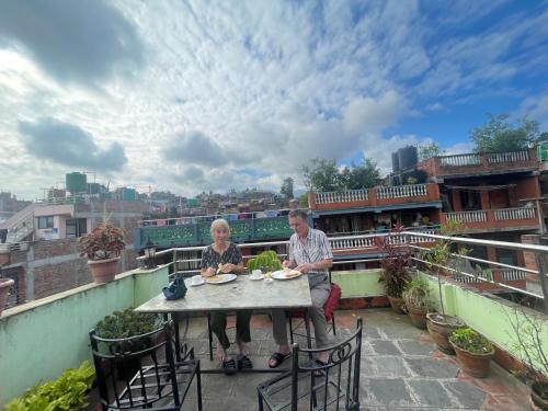 a man and woman sitting at a table on a balcony at Hotel Bhaktapur Inn in Bhaktapur