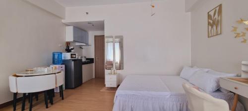ein Schlafzimmer mit einem weißen Bett und einer kleinen Küche in der Unterkunft Auberge at SMDC Hope Residences in Trece Martires