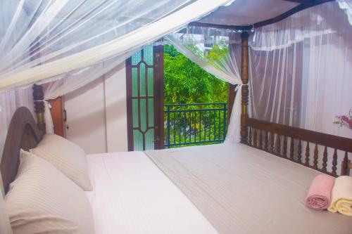 a bedroom with a bed and a balcony with a window at Winsi Villa in Unawatuna