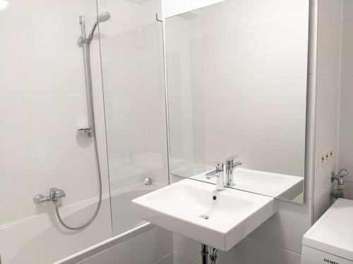 a white bathroom with a sink and a shower at Zentrale Stadtperle, 3 Zimmer, Loggia u. Parkplatz in Karlsruhe