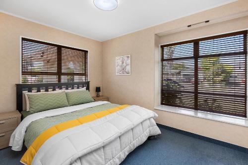een slaapkamer met een groot bed en 2 ramen bij Business Or Holiday with Location, Pool, 4 Bedroom in Hamilton